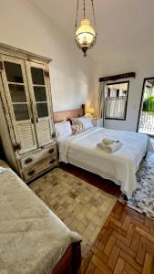 a bedroom with two beds and a chandelier at Pousada das Artes in Tiradentes +57 photos