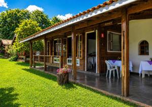 a wooden house with a table in the yard at Sopro do Vento Roots Hotel in Analândia