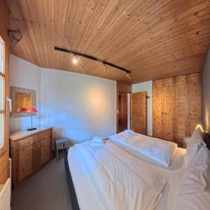 a bedroom with a large bed with a wooden ceiling at Alpen-Retreat mit Spa in Lenzerheide +9 photos