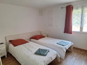 two beds in a small room with a window at Maison Rustrel clim 3 chambres entre ocres et lavandes in Rustrel