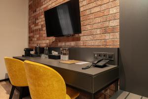 a desk with chairs and a television on a brick wall at Butikowy Hotel M23 Katowice Centrum in Katowice +74 photos