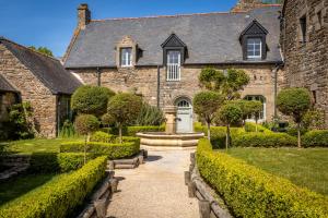 a stone house with a fountain in the front yard at Manoir Des Douets Fleuris in Cancale