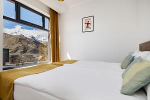 ein Schlafzimmer mit einem Bett und einem Fenster mit Bergblick in der Unterkunft Melodia KAZBEGI in Kazbegi