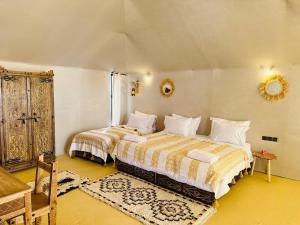 a bedroom with two beds and a mirror on the wall at Camp Merzouga Sand Explorer in Merzouga +26 photos