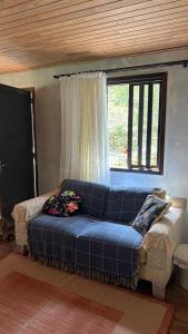 a blue couch in a living room with a window at Sítio Rio Lima in Rio Forcação +3 photos