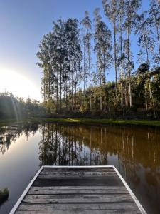 a dock on a lake with trees in the background at Sítio Rio Lima in Rio Forcação