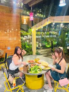 two women sitting at a table with food on it at Bazan Home Mộc Châu in Mộc Châu