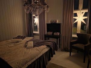 a bedroom with a bed and a chair and a chandelier at Nordgrenska in Åmål
