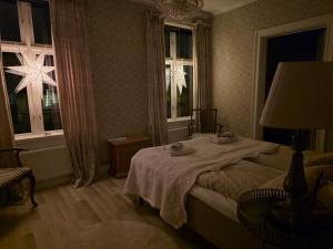 a bedroom with a bed with a table and two windows at Nordgrenska in Åmål