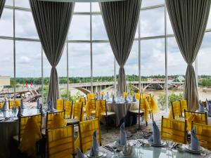 a dining room with tables and yellow chairs and windows at Diamond Stars Ben Tre Hotel in Ben Tre