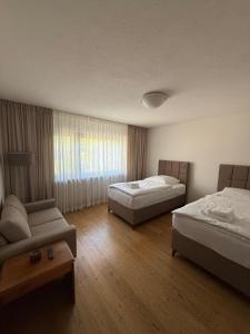a hotel room with two beds and a couch at Casa Emilio in Rüsselsheim
