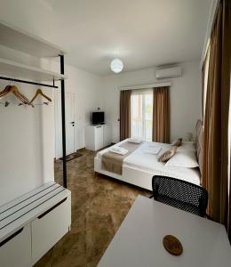 a hotel room with a bed and a table and a television at Seli's White Villa in Ksamil