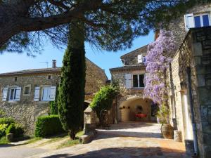 an old stone house with a tree and purple flowers at Chambres d'hôtes Mas Lassagne in Vagnas