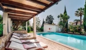 a pool with chaise lounge chairs next to a house at Casa Porta Azul in Boliqueime