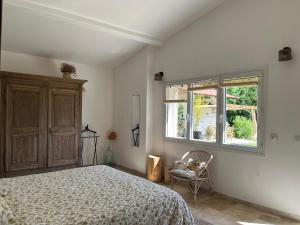 a bedroom with a bed and a window and a chair at La Clairière de l'Ange Havre de paix en Drôme des Collines in Peyrins