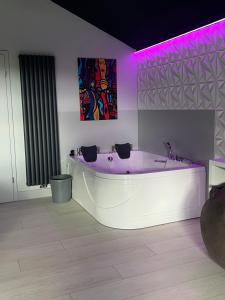 a large white tub in a room with purple lighting at Künstlerhaus Vulkaneifel in Mückeln +35 photos