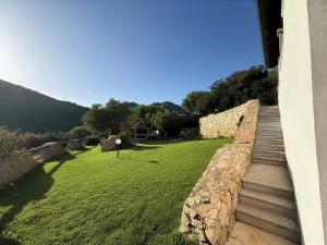 a stone retaining wall with a grassy yard at Villa Olbia mare in Olbia