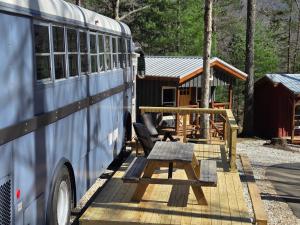 a bus parked next to a picnic table and a cabin at Lazy T Cabins - The Skoolie in Robbinsville +9 photos