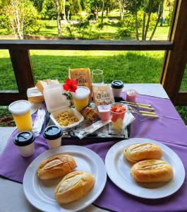 a table with plates of food and drinks on it at Sopro do Vento Roots Hotel in Analândia