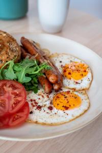 a plate of eggs and sausage and tomatoes on a table at Beskid Balans & SPA in Krynica Zdrój