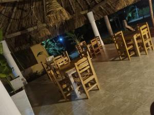 a row of wooden chairs on a patio at night at Hostal nido tortuga in San Antero