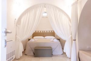 a bedroom with a canopy bed with white curtains at Trullo MaPì in San Michele Salentino +18 photos