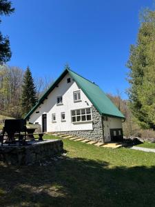 a white barn with a green roof on a field at Forest Escape House in Begovo Razdolje