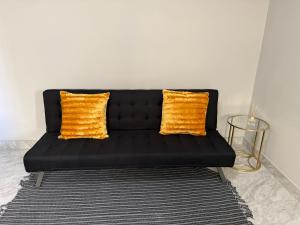 a black couch with two orange pillows on a rug at J&A Corner - Swakopmund in Swakopmund
