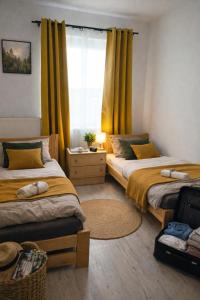 a bedroom with two beds and a window with yellow curtains at Komfortowe Apartamenty i Pokoje Powidz in Powidz +8 photos