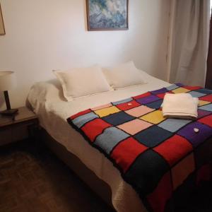 a bed with a colorful blanket on top of it at Chalet de Irurtia in Carmelo