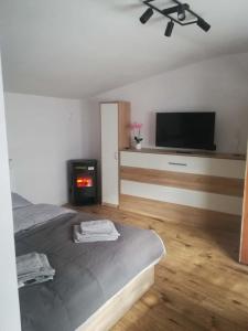 a bedroom with a bed and a flat screen tv at Chatka Czesia in Sosnówka