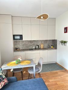 a kitchen with a table and two chairs and a counter at Apartamentai Vetrungiu g 3 in Nida