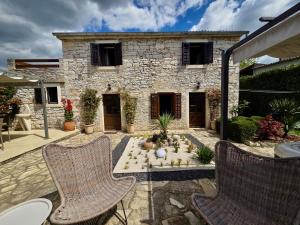 a patio with two chairs and a stone house at Stonehouse Ana with Jacuzzi Rovinj-Krmed in Krmed