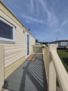 a house with a wooden deck next to a building at Jams Caravan in Skegness