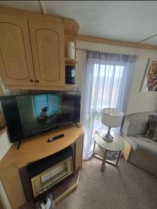 a small living room with a tv and a couch at Jams Caravan in Skegness