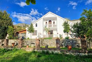 a white house behind a stone wall at Hidden Gem Villa in Guri i Zi