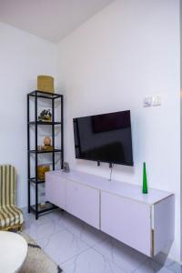 a living room with a tv on a white wall at Artist sanctuary lakeview phase4 in Mto Panga +5 photos