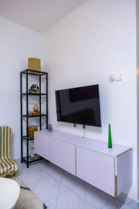a living room with a tv on a white wall at Artist sanctuary lakeview phase4 in Mto Panga