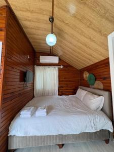 a bed in a room with a wooden ceiling at Kuba pansiyon in Side