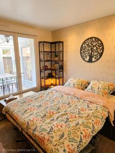 a bedroom with a bed with a tree on the wall at Le passage, maisonnette cosy classée 4 étoiles in Pont-lʼÉvêque