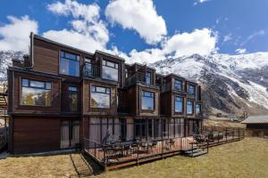 Ein großes Holzhaus mit Bergen im Hintergrund in der Unterkunft Melodia KAZBEGI in Kazbegi