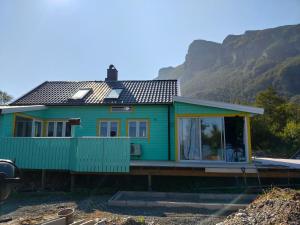 a green house with a mountain in the background at Høgberget Loft with 3 bedrooms and private bathroom in Skotten