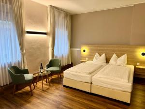 ein Schlafzimmer mit einem Bett, zwei Stühlen und einem Tisch in der Unterkunft Hotel Feldmann in Münster