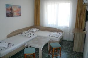 a room with two beds and a table and chairs at Къща за гости Мишел in Nesebar
