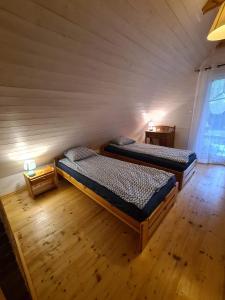 a bedroom with two beds in a room with a wall at Dom wakacyjny nad jeziorem, Mazury in Samin
