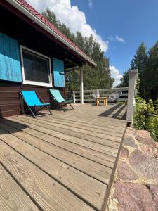 a wooden deck with two chairs and a table on a house at Dom wakacyjny nad jeziorem, Mazury in Samin