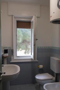 a bathroom with a sink and a toilet and a window at Appartamento l'Isola D'Oro in Grado