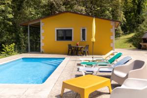 a yellow house with a swimming pool and chairs at Casinha de campo in Geres