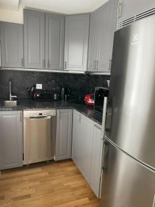 a kitchen with white cabinets and a stainless steel refrigerator at Fully equipped guest apartment with parking in Upplands-Väsby +4 photos