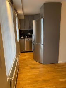 a stainless steel refrigerator in a kitchen with wooden floors at Fully equipped guest apartment with parking in Upplands-Väsby